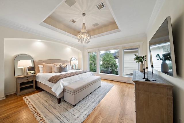 bedroom with visible vents, light wood-style flooring, and a raised ceiling