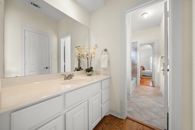 full bath with visible vents, vanity, and wood finished floors