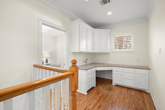 unfurnished office with visible vents, light wood-style flooring, recessed lighting, ornamental molding, and built in desk