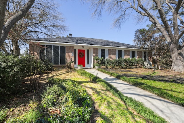 single story home featuring a sunroom and brick siding