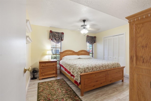 bedroom featuring a textured ceiling, ceiling fan, baseboards, a closet, and light wood finished floors