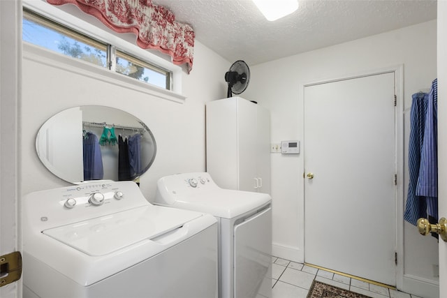 washroom featuring laundry area, washing machine and dryer, a textured ceiling, and light tile patterned flooring