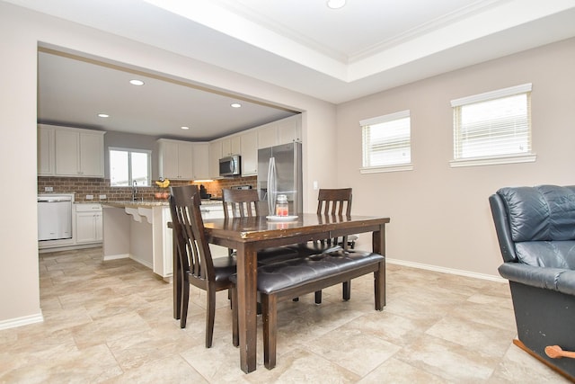 dining room featuring a raised ceiling, recessed lighting, baseboards, and ornamental molding