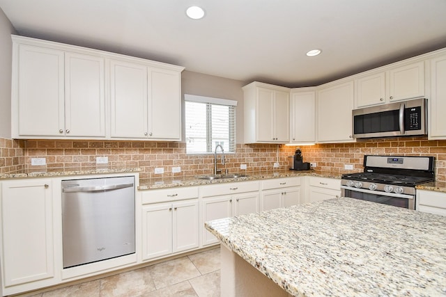 kitchen with a sink, backsplash, appliances with stainless steel finishes, and white cabinetry