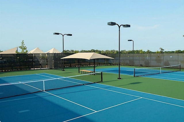 view of tennis court with community basketball court and fence
