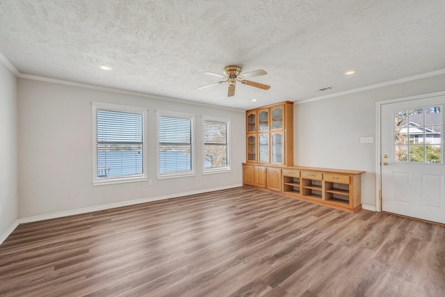 unfurnished living room with wood finished floors, visible vents, and crown molding