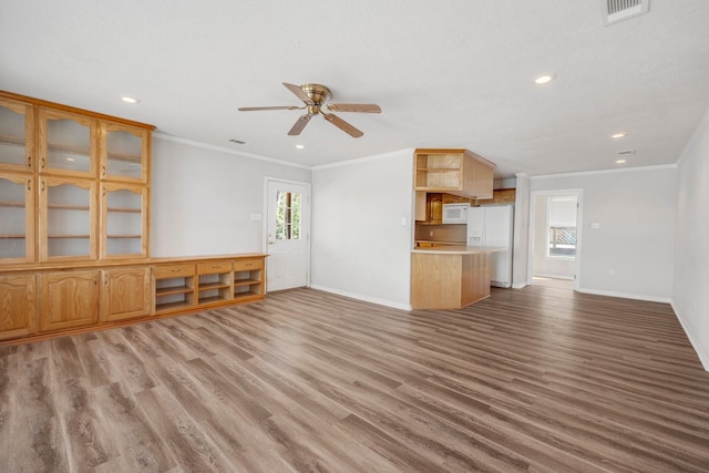 unfurnished living room with visible vents, crown molding, light wood-style flooring, and baseboards