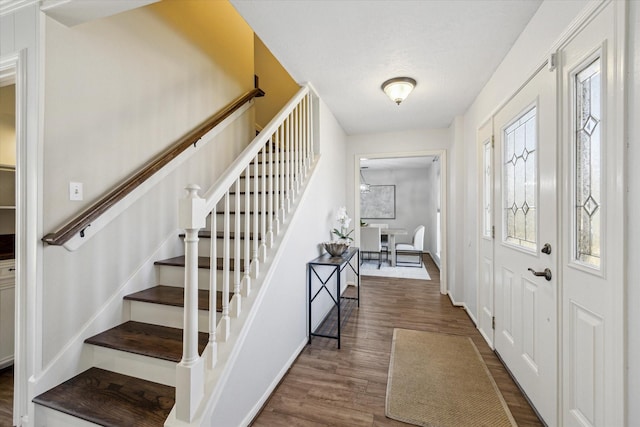 entrance foyer with dark wood-style floors, stairs, and baseboards