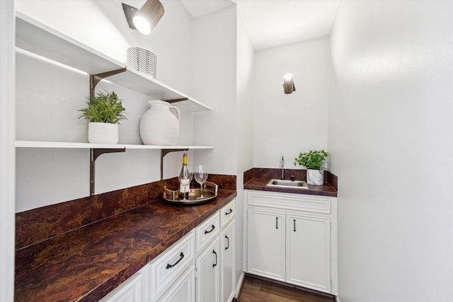 bar with dark wood-type flooring, indoor wet bar, and a sink