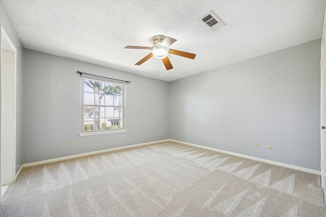 unfurnished room with carpet, visible vents, ceiling fan, a textured ceiling, and baseboards