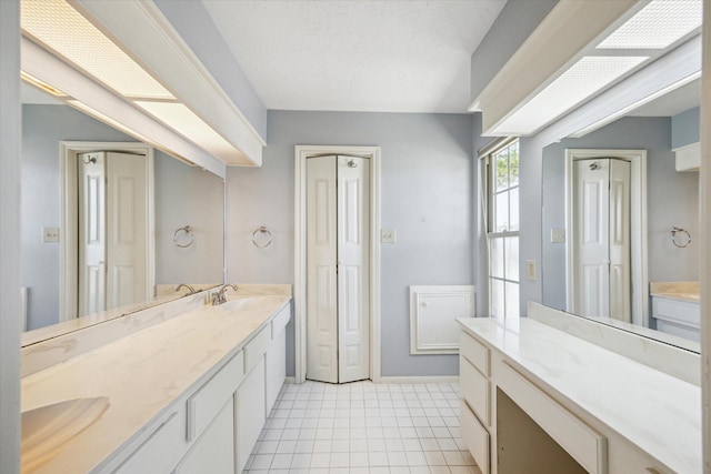 bathroom with baseboards, double vanity, a sink, and tile patterned floors