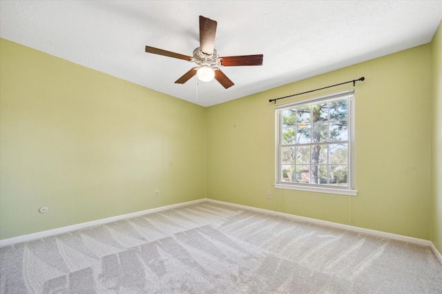 empty room featuring ceiling fan, baseboards, a textured ceiling, and light colored carpet