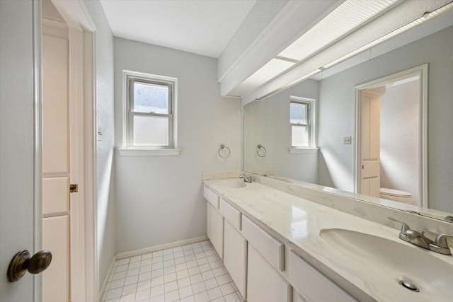 bathroom with baseboards, a sink, toilet, and tile patterned floors