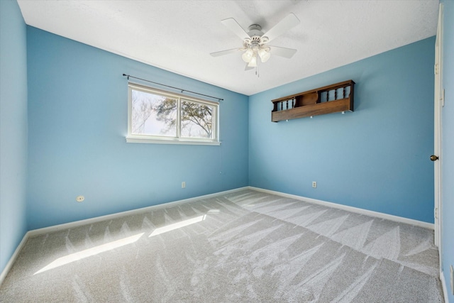 carpeted empty room featuring baseboards and a ceiling fan