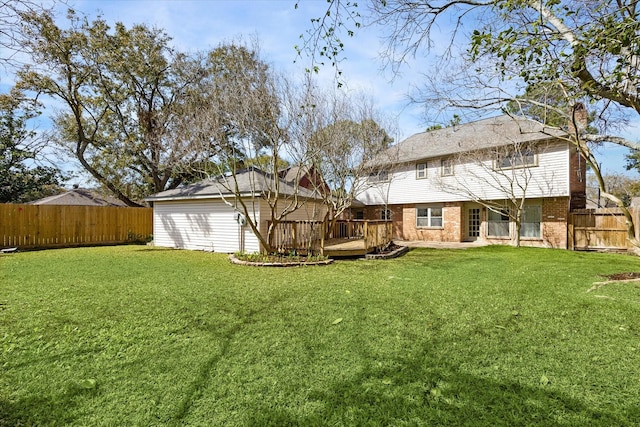 back of property with a fenced backyard, brick siding, a wooden deck, and a lawn