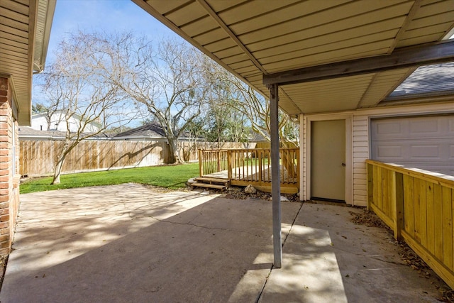 view of patio featuring a garage, fence, and a wooden deck