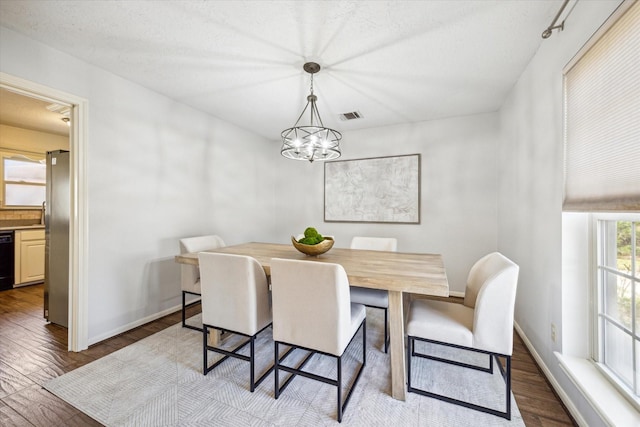 dining area featuring a chandelier, visible vents, dark wood finished floors, and baseboards