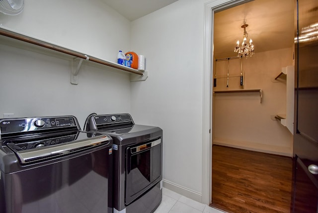 washroom featuring laundry area, light tile patterned floors, baseboards, a chandelier, and separate washer and dryer