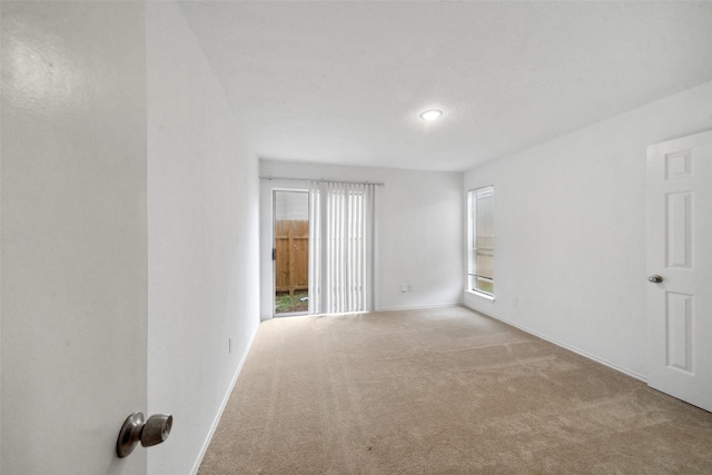 carpeted spare room featuring baseboards