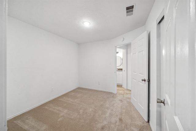 unfurnished bedroom with baseboards, light colored carpet, visible vents, and a textured ceiling