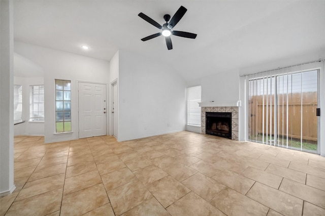 unfurnished living room featuring lofted ceiling, ceiling fan, a tiled fireplace, and light tile patterned flooring