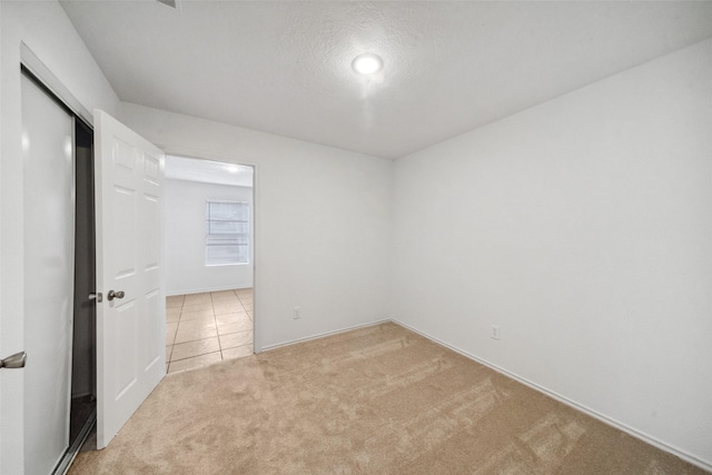 carpeted empty room with a textured ceiling and tile patterned flooring