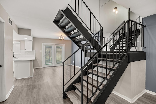 stairway with a chandelier, visible vents, baseboards, and wood finished floors