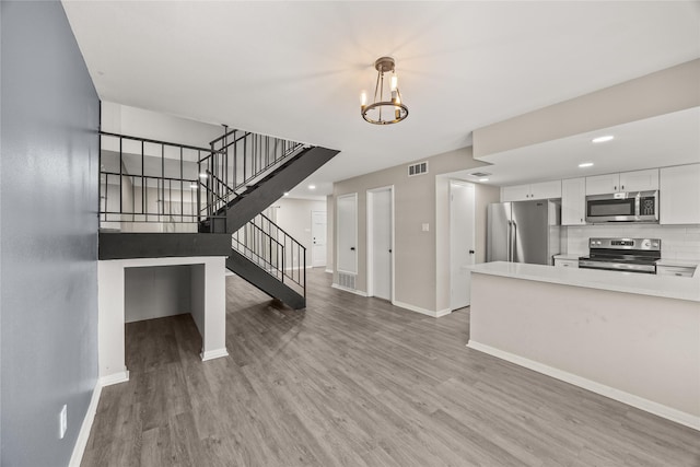 unfurnished living room featuring visible vents, light wood-style flooring, baseboards, and stairs