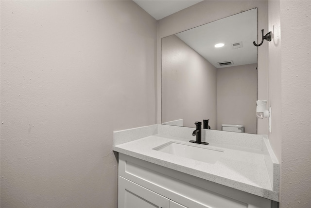 half bath with visible vents, vanity, and toilet