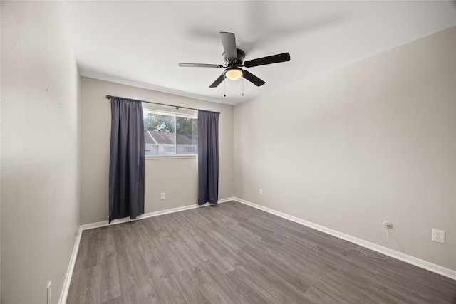 empty room featuring ceiling fan, baseboards, and wood finished floors