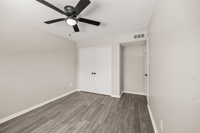 unfurnished bedroom featuring wood finished floors, a ceiling fan, visible vents, baseboards, and a closet