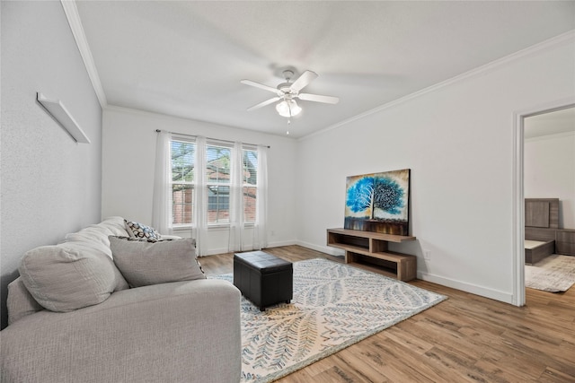 living area featuring baseboards, ornamental molding, ceiling fan, and wood finished floors