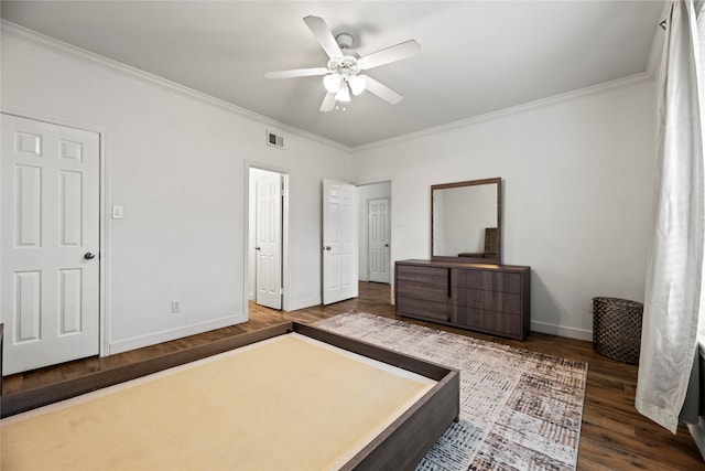 bedroom with baseboards, wood finished floors, visible vents, and crown molding