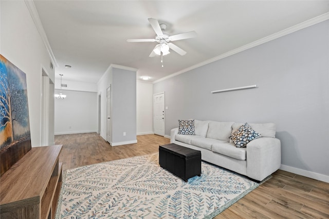 living area with crown molding, baseboards, wood finished floors, and ceiling fan with notable chandelier