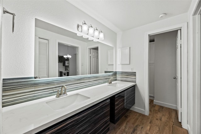 bathroom with double vanity, baseboards, a sink, and wood finished floors