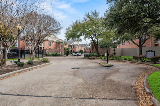 view of road featuring a residential view, a gated entry, street lights, and curbs