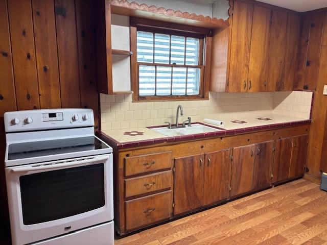 kitchen featuring tile countertops, white electric stove, brown cabinetry, and a sink