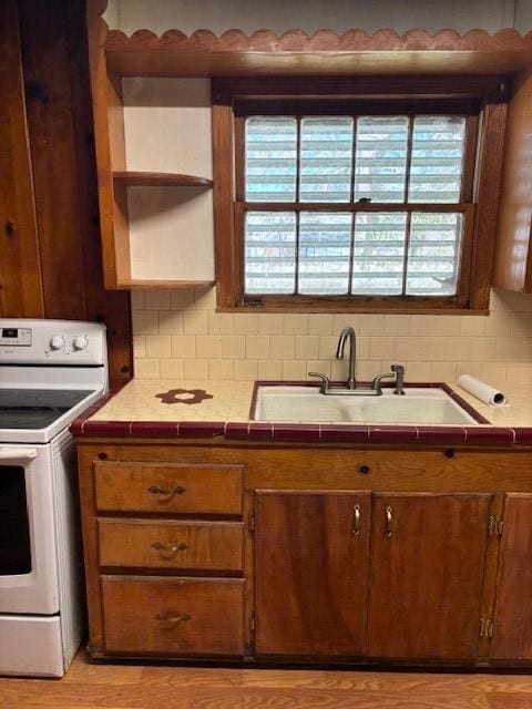 kitchen with a wealth of natural light, white range with electric stovetop, decorative backsplash, and a sink