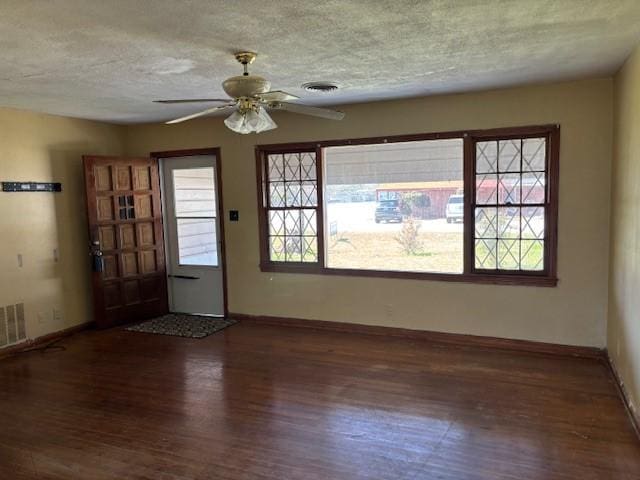 spare room featuring a healthy amount of sunlight, a textured ceiling, and wood finished floors