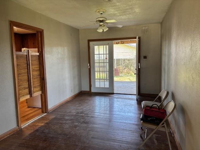 doorway featuring a ceiling fan, baseboards, and wood finished floors