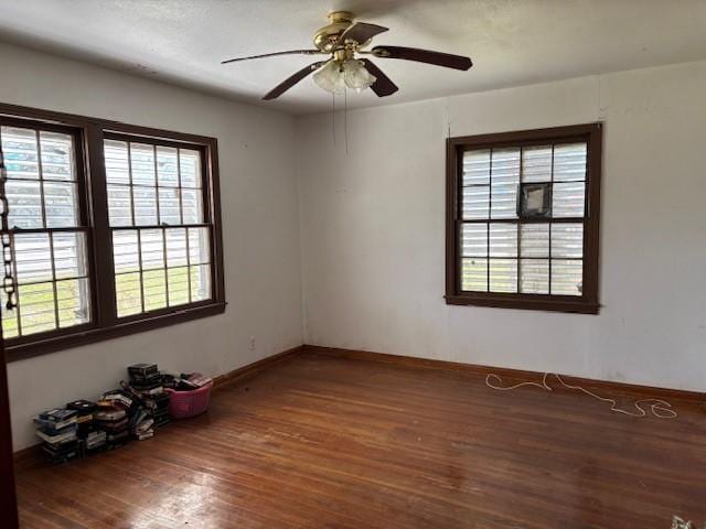 spare room featuring a ceiling fan, plenty of natural light, baseboards, and wood finished floors