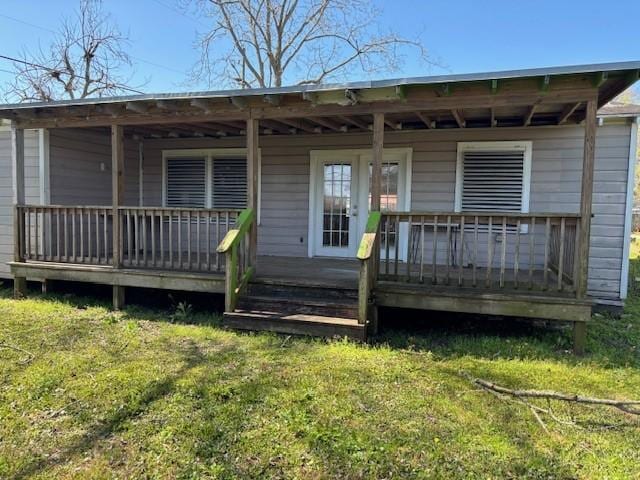 rear view of house featuring covered porch and a lawn