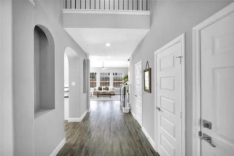 corridor featuring arched walkways, dark wood finished floors, and baseboards