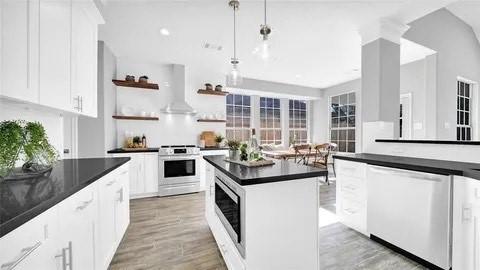 kitchen featuring dark countertops, dishwashing machine, wall chimney exhaust hood, stove, and open shelves