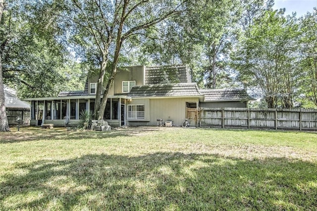 back of property featuring mansard roof, a lawn, fence, and a sunroom