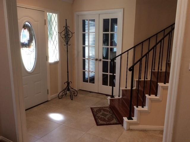 entrance foyer featuring tile patterned flooring, french doors, baseboards, and stairs