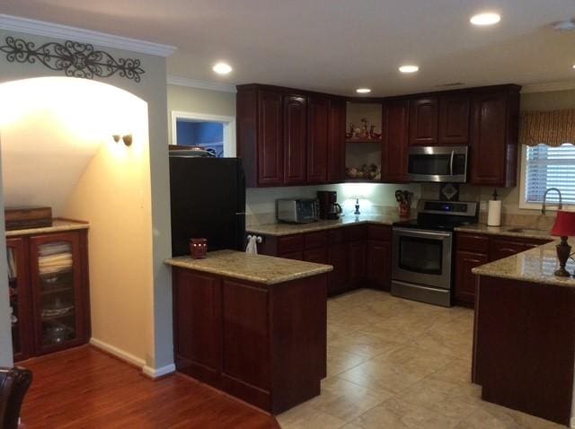 kitchen with stainless steel appliances, a peninsula, a sink, and crown molding