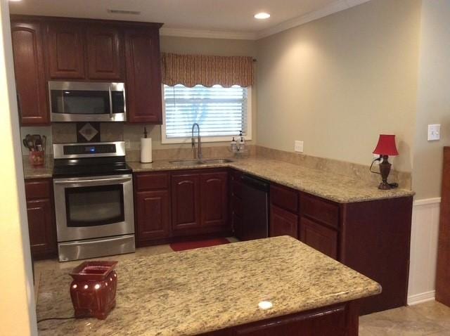 kitchen with stainless steel appliances, ornamental molding, a sink, and light stone countertops