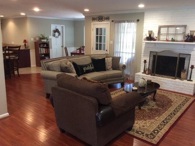 living area featuring recessed lighting, a fireplace, wood finished floors, and crown molding