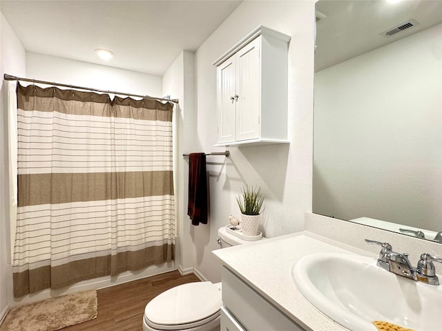 bathroom featuring toilet, visible vents, wood finished floors, and vanity